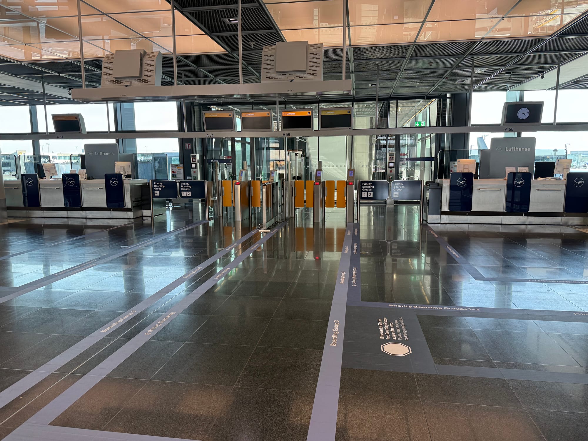 An airport gate, not currently in use. On the floor, rectangles in various shades of blue have been drawn with various boarding groups labelled.