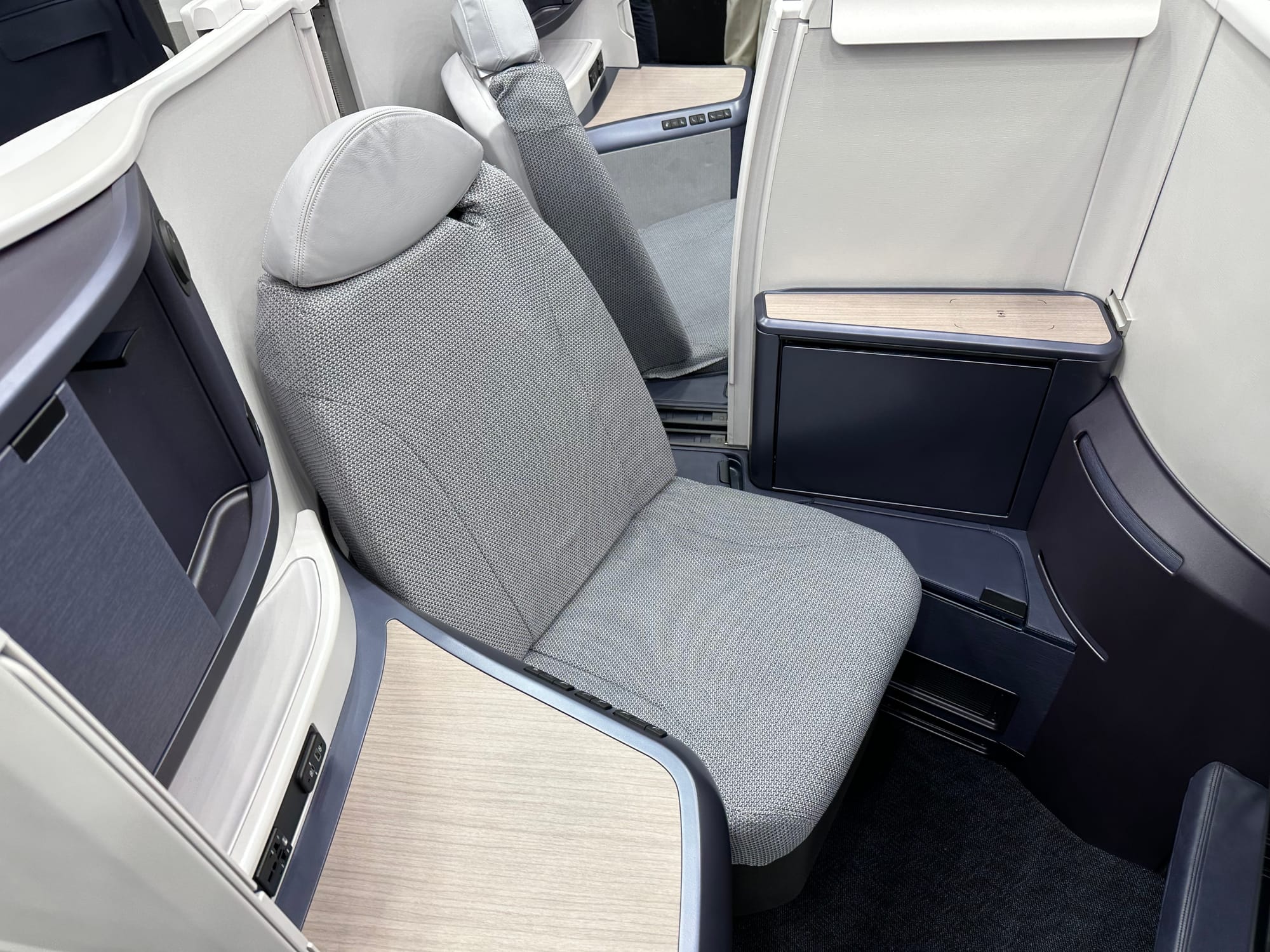 Airline seat at trade show. It is a herringbone seat facing the camera standing in what would be the aisle.