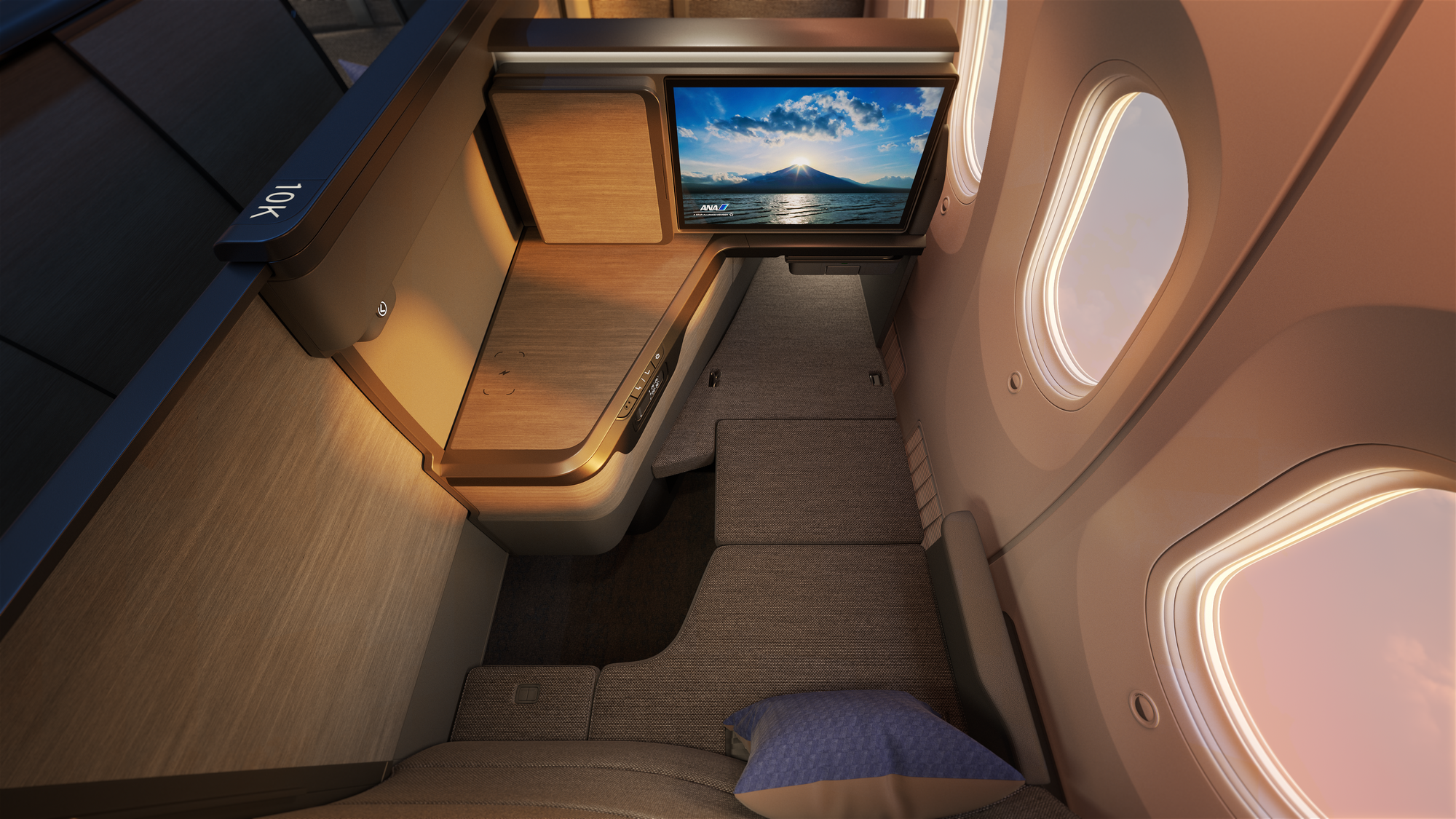 Interior, business class cabin, closeup on business seat, overhead looking forward. A small riser meets the ottoman and seat to create a wide bed.