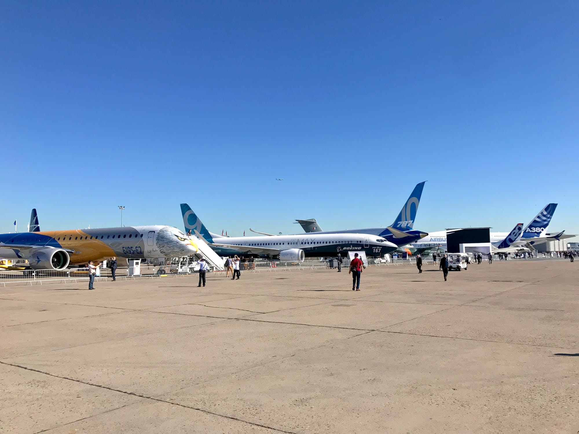 Wide shot of Le Bourget main static area, relatively few people. L-R: E195, 939 MAX 9, 787-10, A400M, A320neo (family), A380 (with Plus winglets)