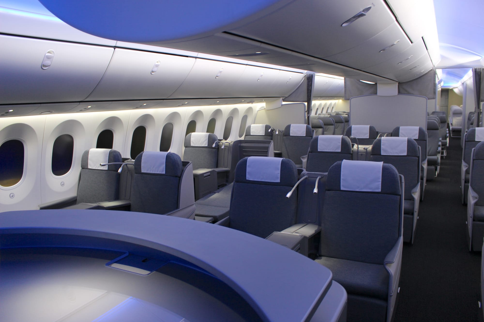 Interior, cabin mockup demonstrator. Ranks of business, premium and economy seats stretch back through the mockup, in a way that sort of looks like a normal cabin at first glance but then the different seat types and models come into focus.