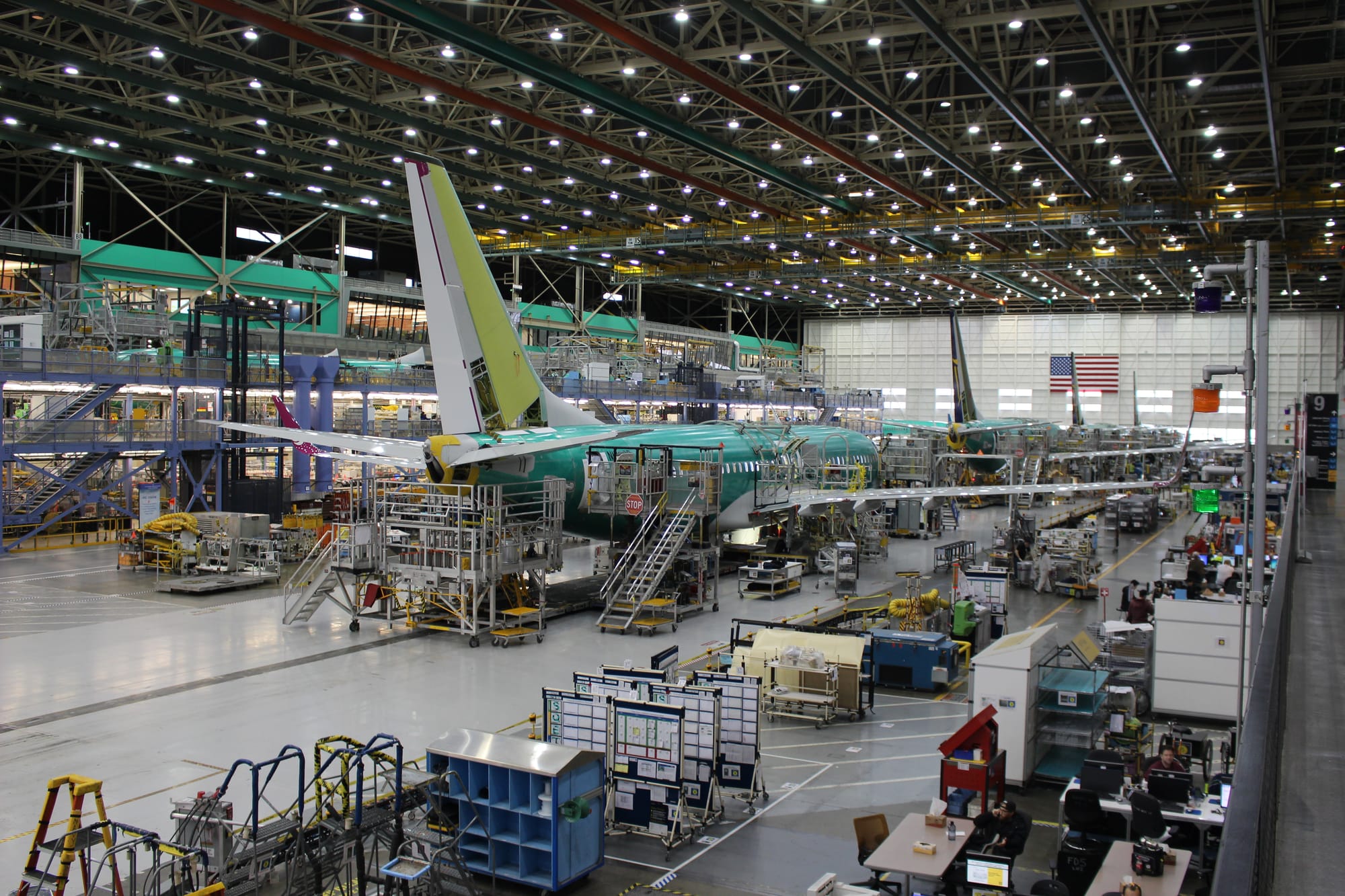 Interior, Boeing factory. Two mostly green 737 NGs are being assembled.