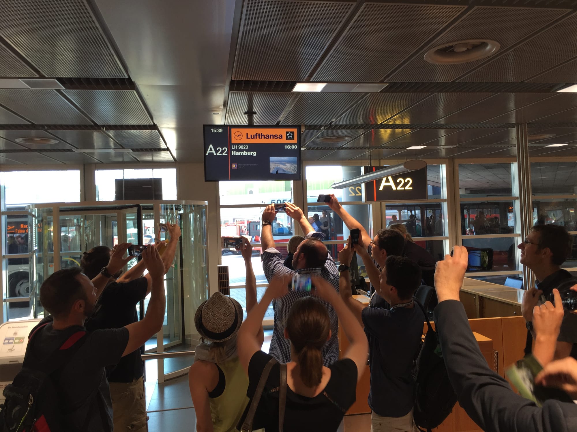 A dozen or so people taking pictures of the gate sign.
