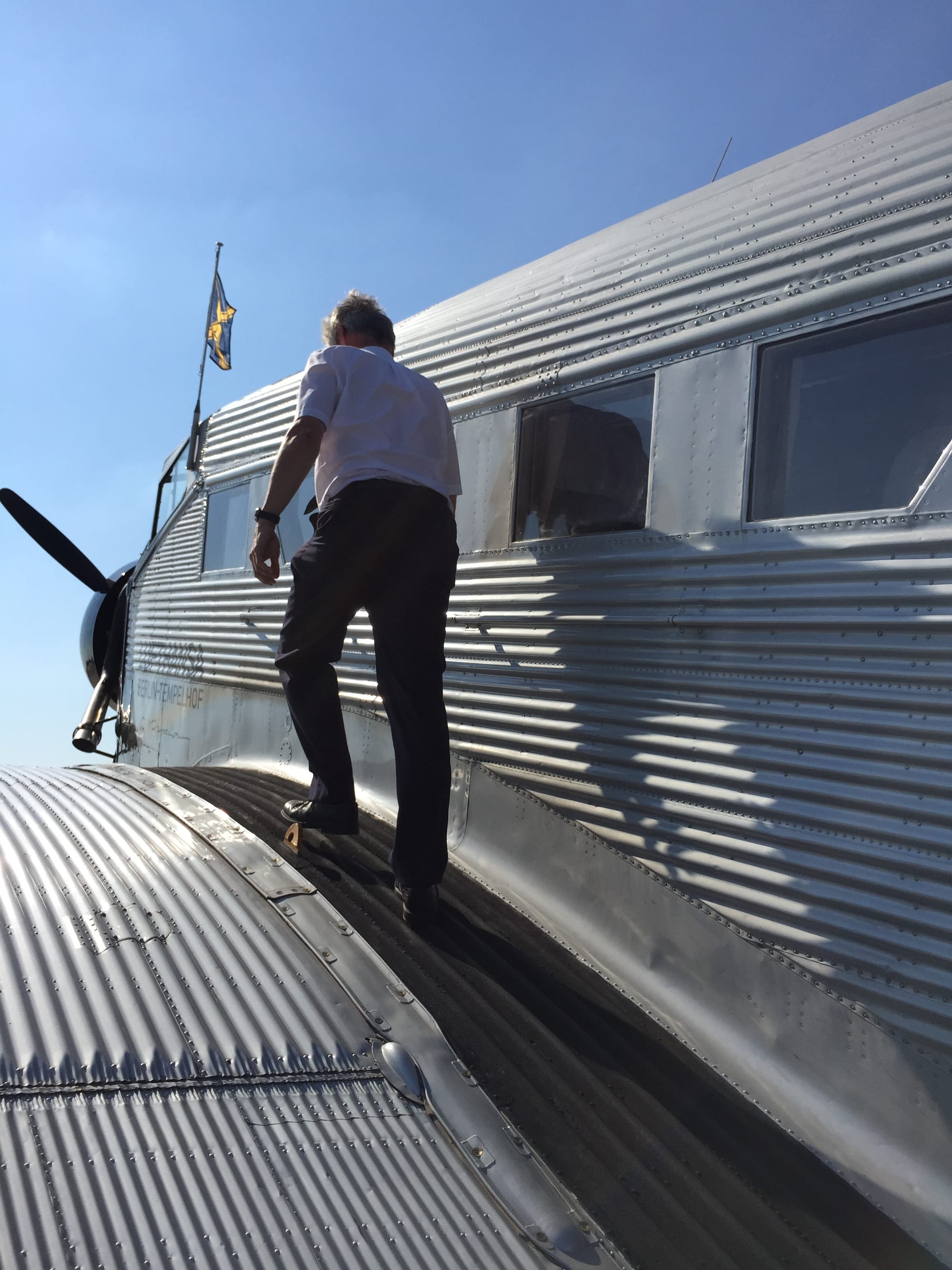 Closeup on the left wing: a pilot walks up the black-painted section immediately next to the cabin.