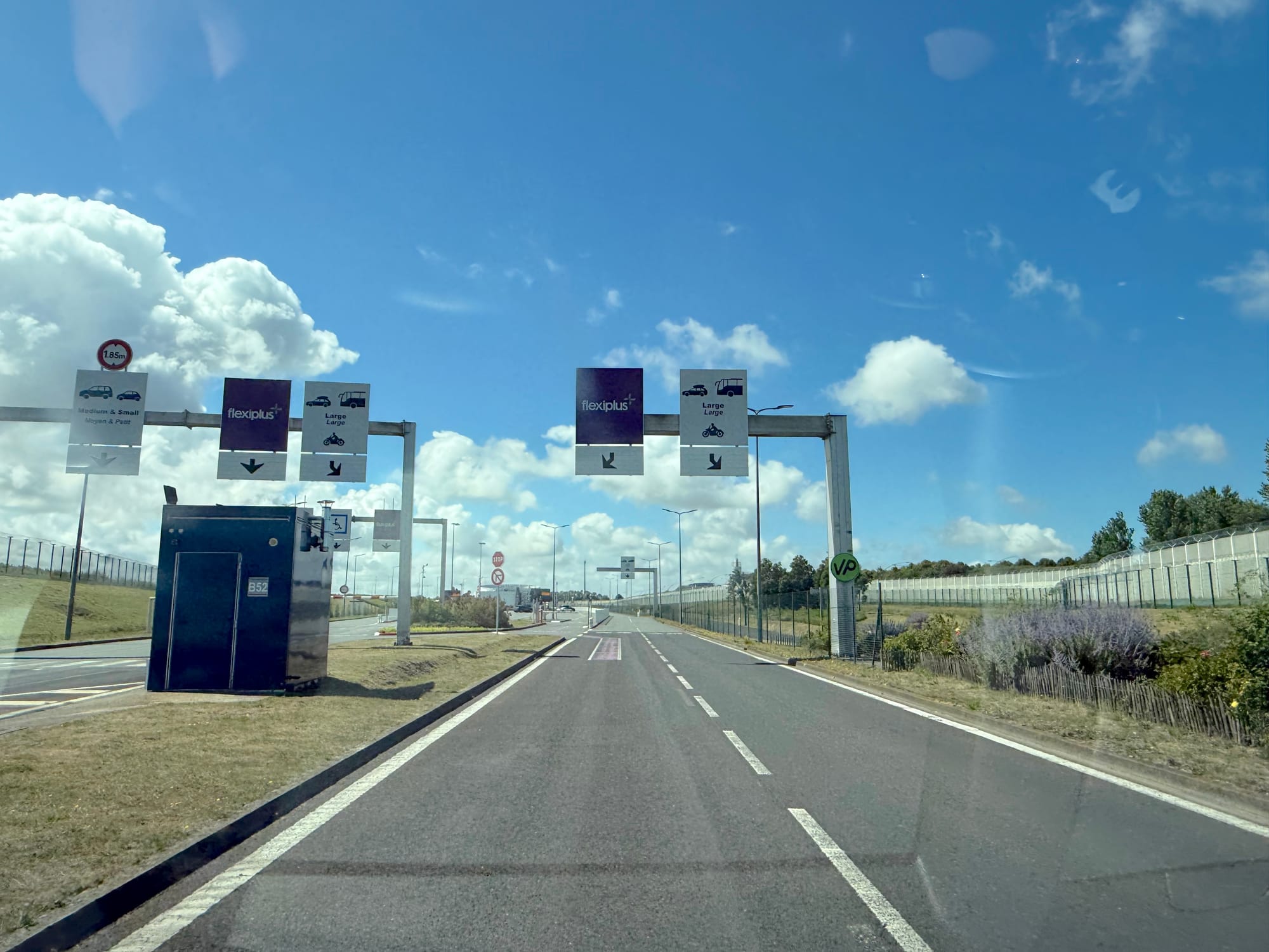 Photo from inside a car driving towards the boardin garea, in lanes with "Flexiplus" and "Large" options. To the left are "medium and small" options.