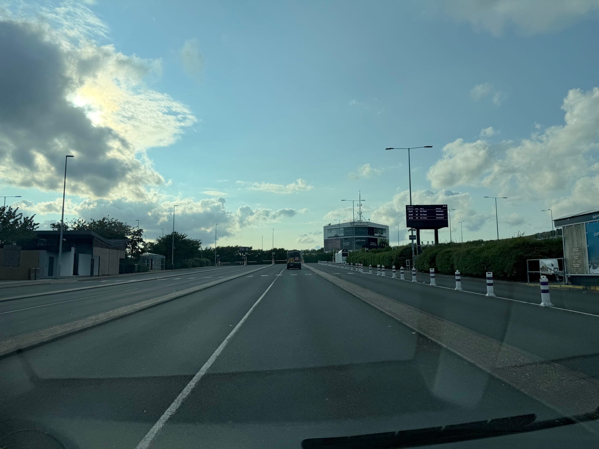 A half dozen lines for traffic to queue. To the left is a small toilet block and vending machines. Ahead is a control centre-looking sort of building and a departures screen that is, at this far distance, illegible.