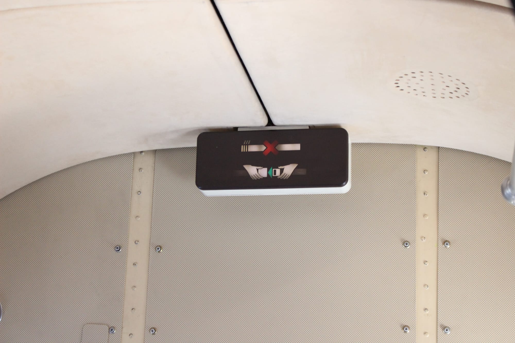 Closeup on a lighted no smoking/fasten seatbelts sign at the front of the cabin