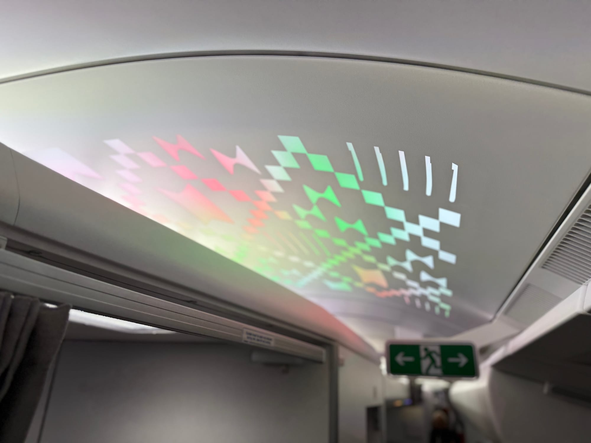 Overhead backlit panel with woven motif in multiple colours.