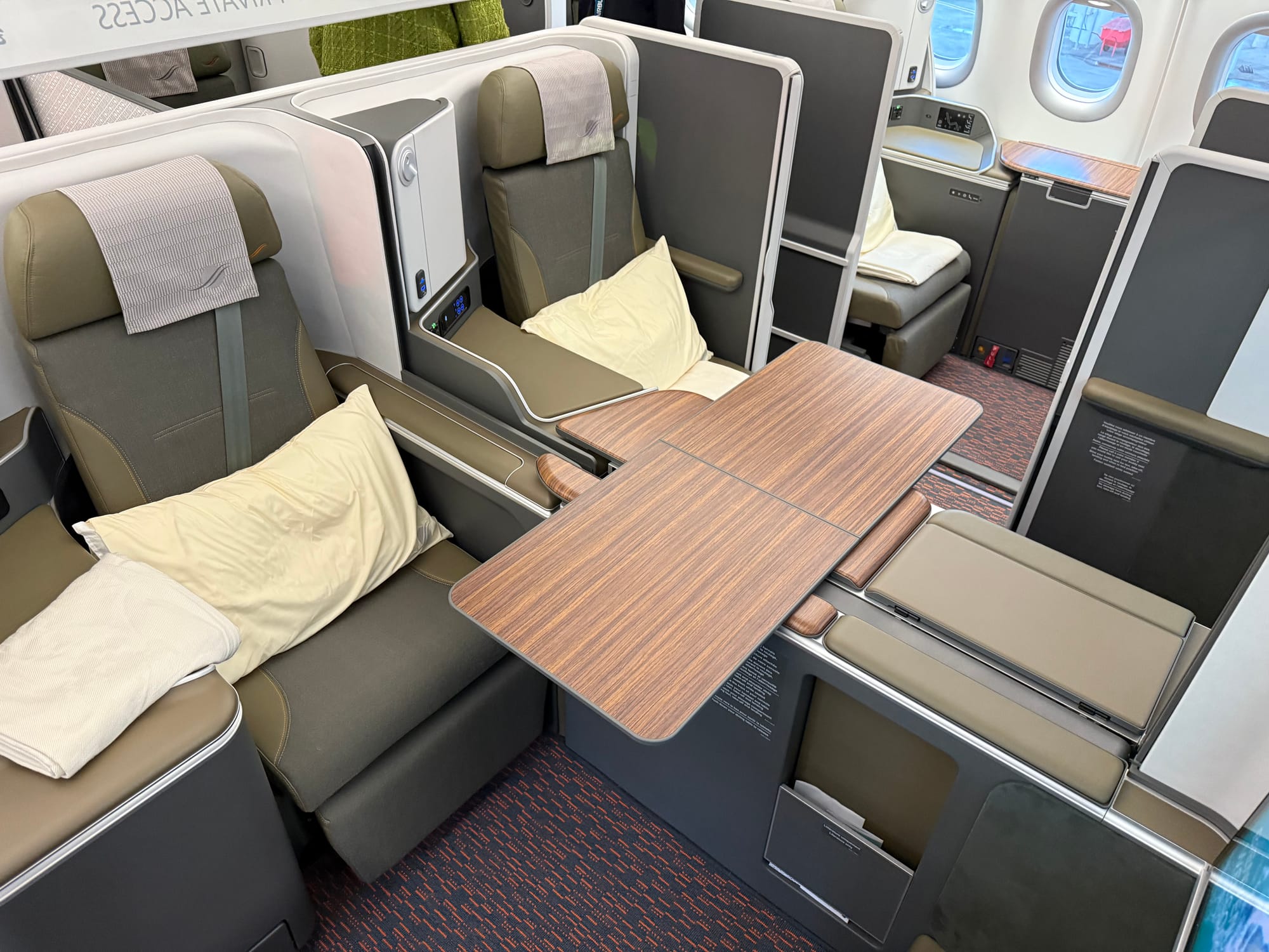 Interior, studio class cabin. The divider between the centre pair of seats is down and the double table in a wood effect has been deployed.