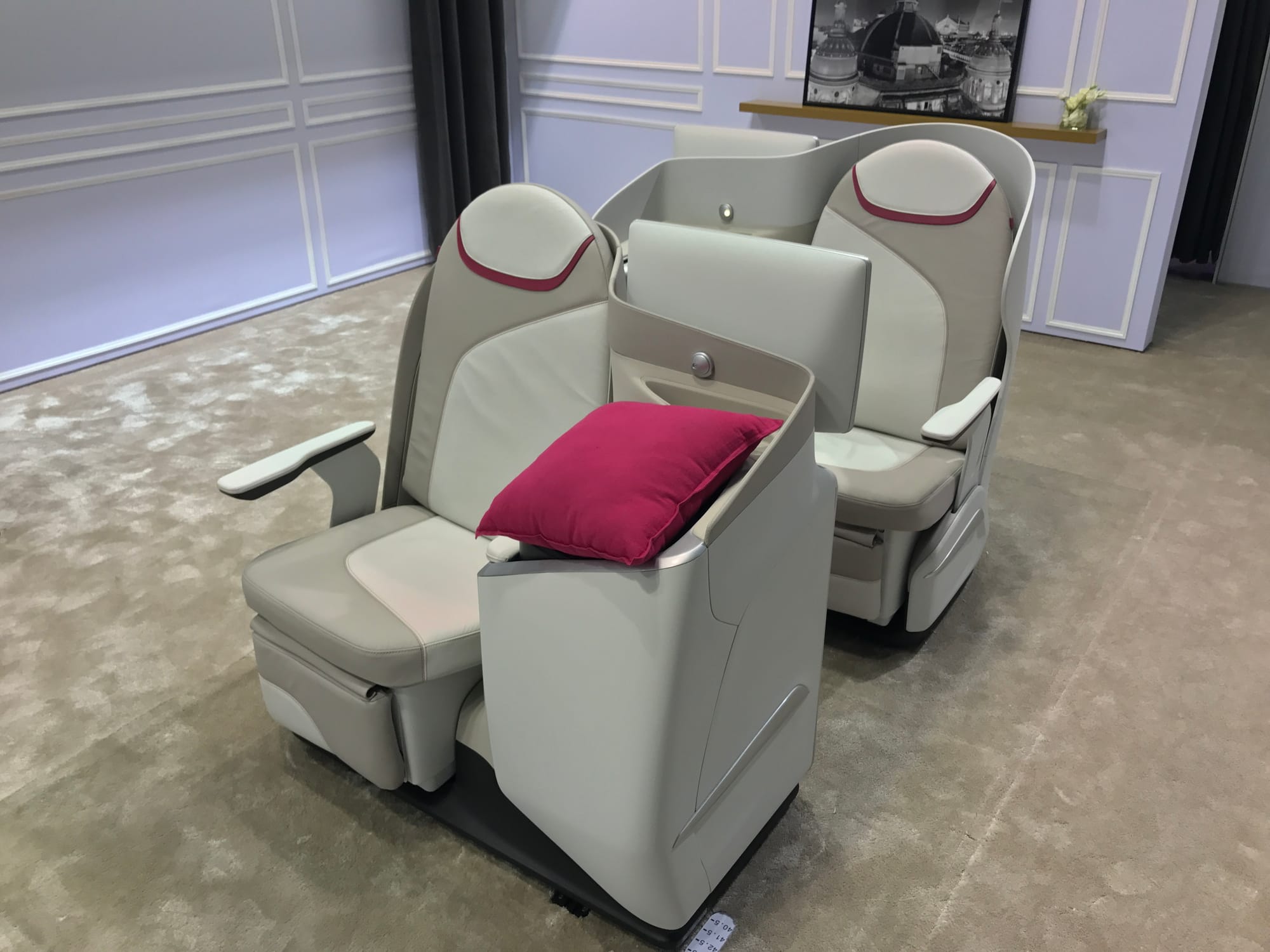 Trade show stand with simple grey staggered seat with burgundy accents.