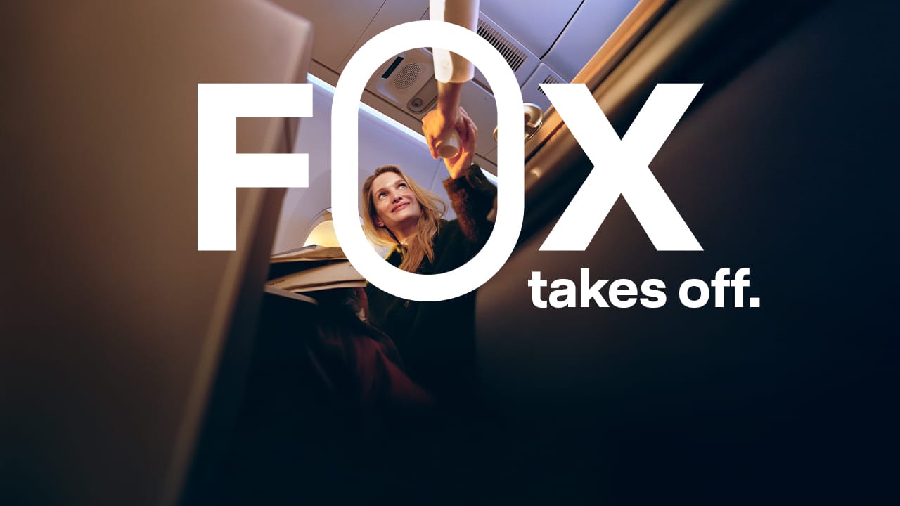 A passenger in business class receives a drink from, presumably, a flight attendant.