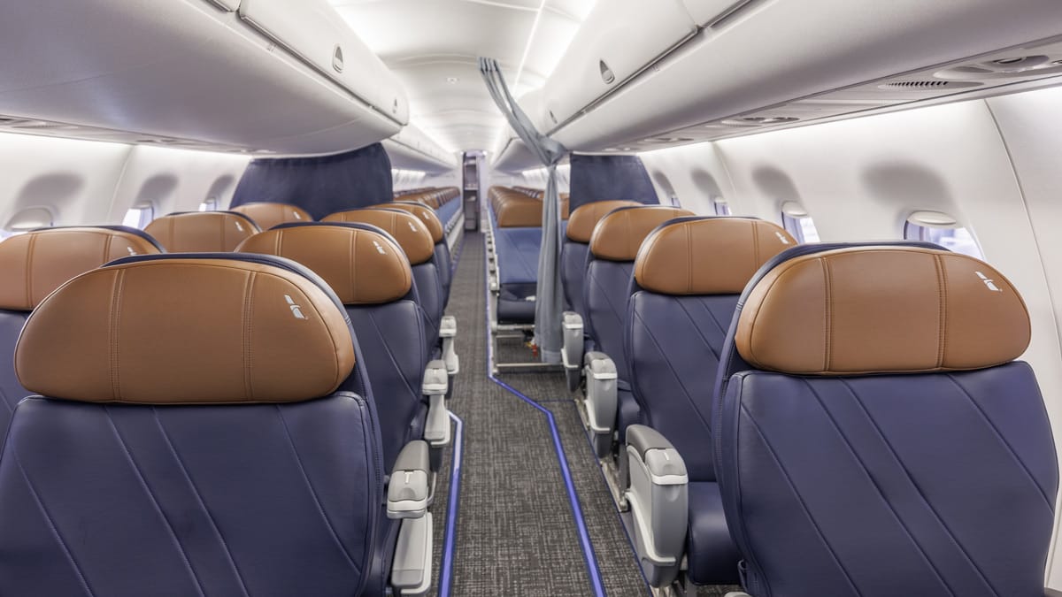 Interior, E170/175, 1-2 domestic first cabin with 2-2 economy beyond. The seats are blue with ugly mid-brown headrests.