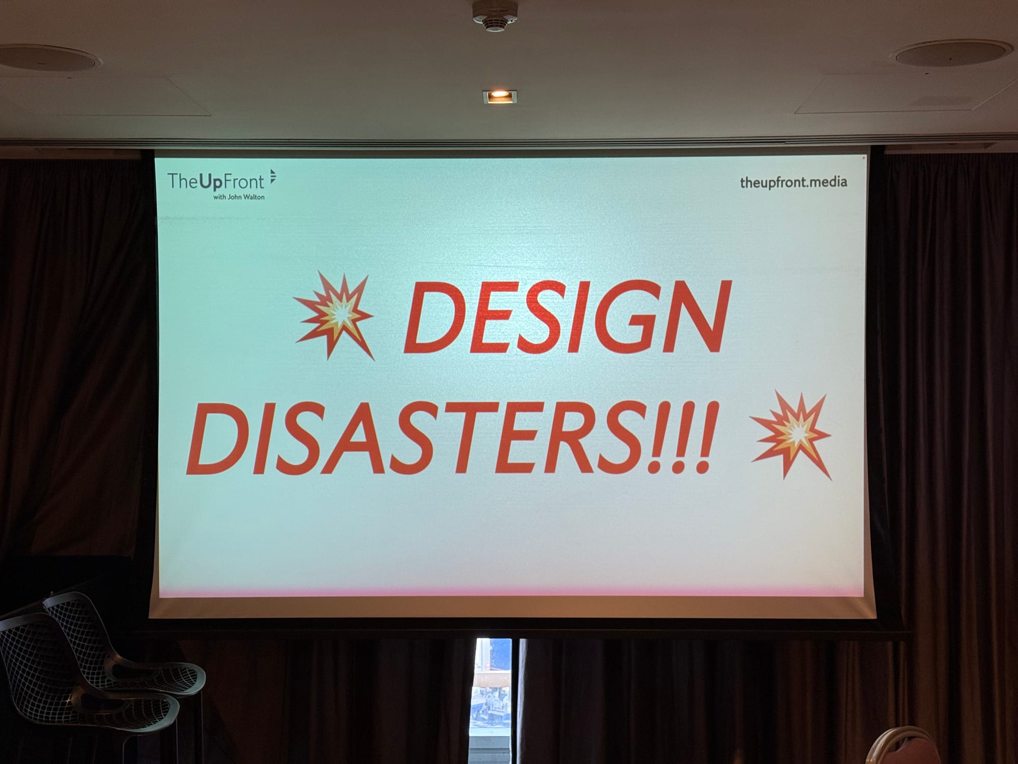 A screen with a slide on it containing The Up Front's logo, our website, and "DESIGN DISASTERS!!!" in red italic allcaps with explosion emojis.