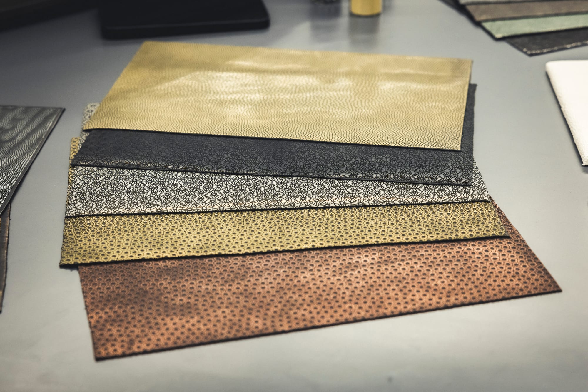 Five different types colours and patterns of a metal-effect material sit on a display surface.