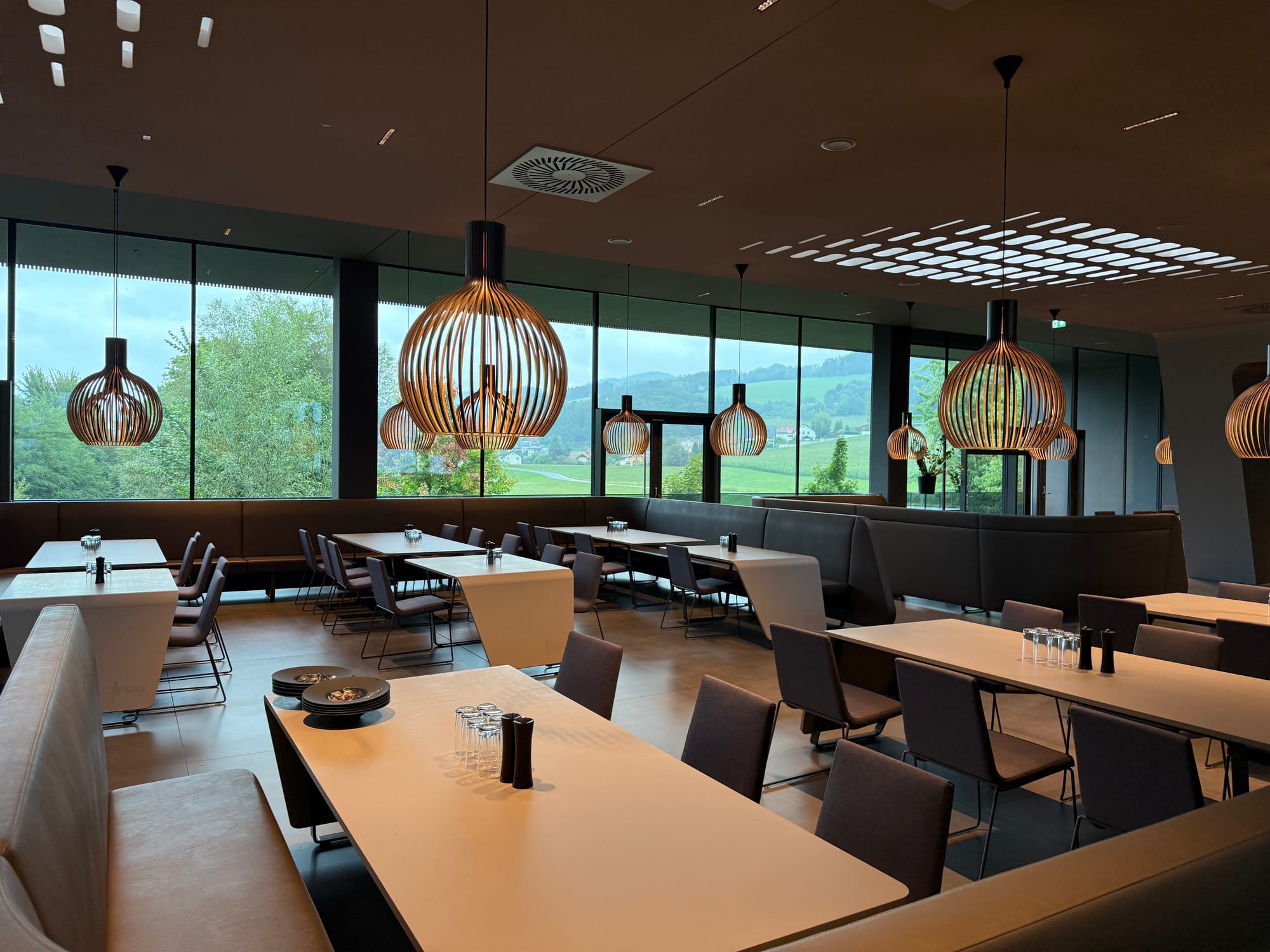 Interior, modern glass-walled restaurant with modern tables of 2-12 seats.