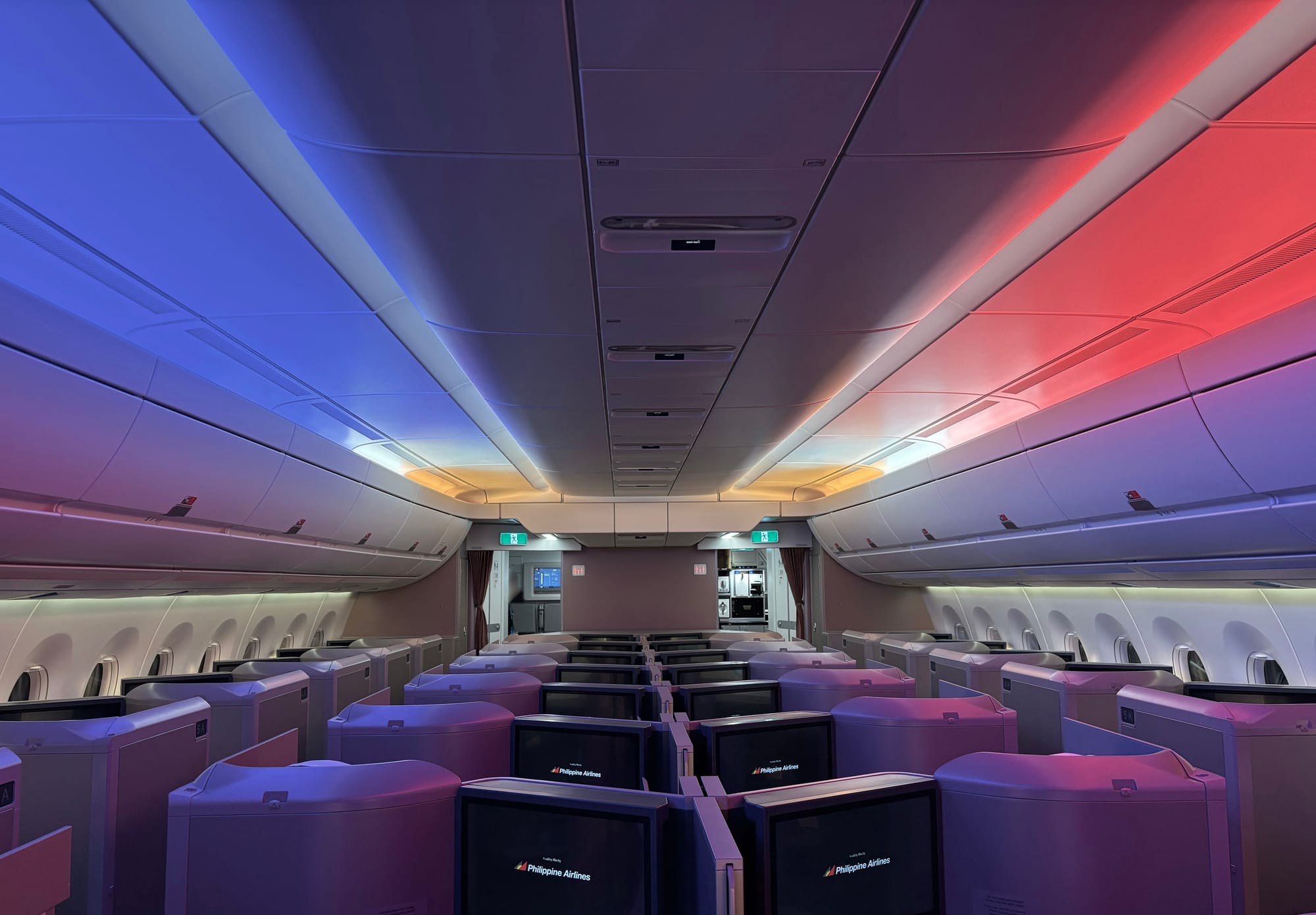 Looking forwards in the business cabin: on the ceiling at the front there is a gold and white section, with blue lights on the left and red lights on the right, like the national flag of the Philippines.