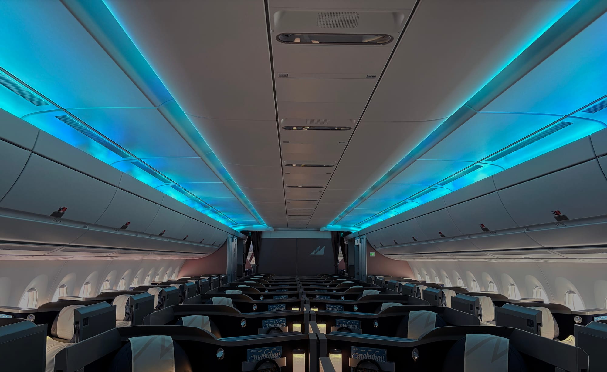 View of the business cabin from the front, showing rippling blue and green lights on the ceiling.