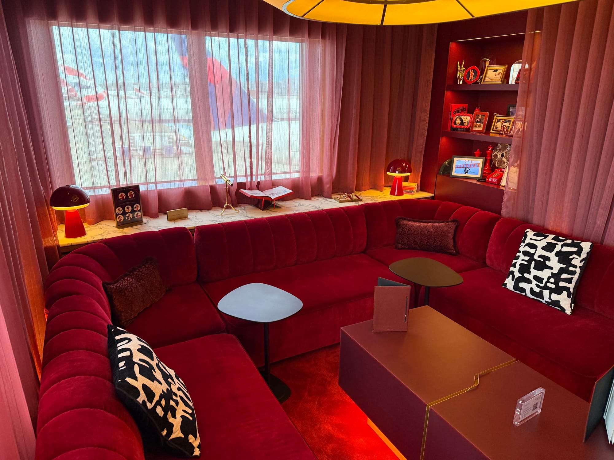 Interior, The Royal Box. U-shaped red velvet sofas with red curtains, carpet and furnishings, looking glam. Beyond it on the apron are a Delta tail and a few BA tails