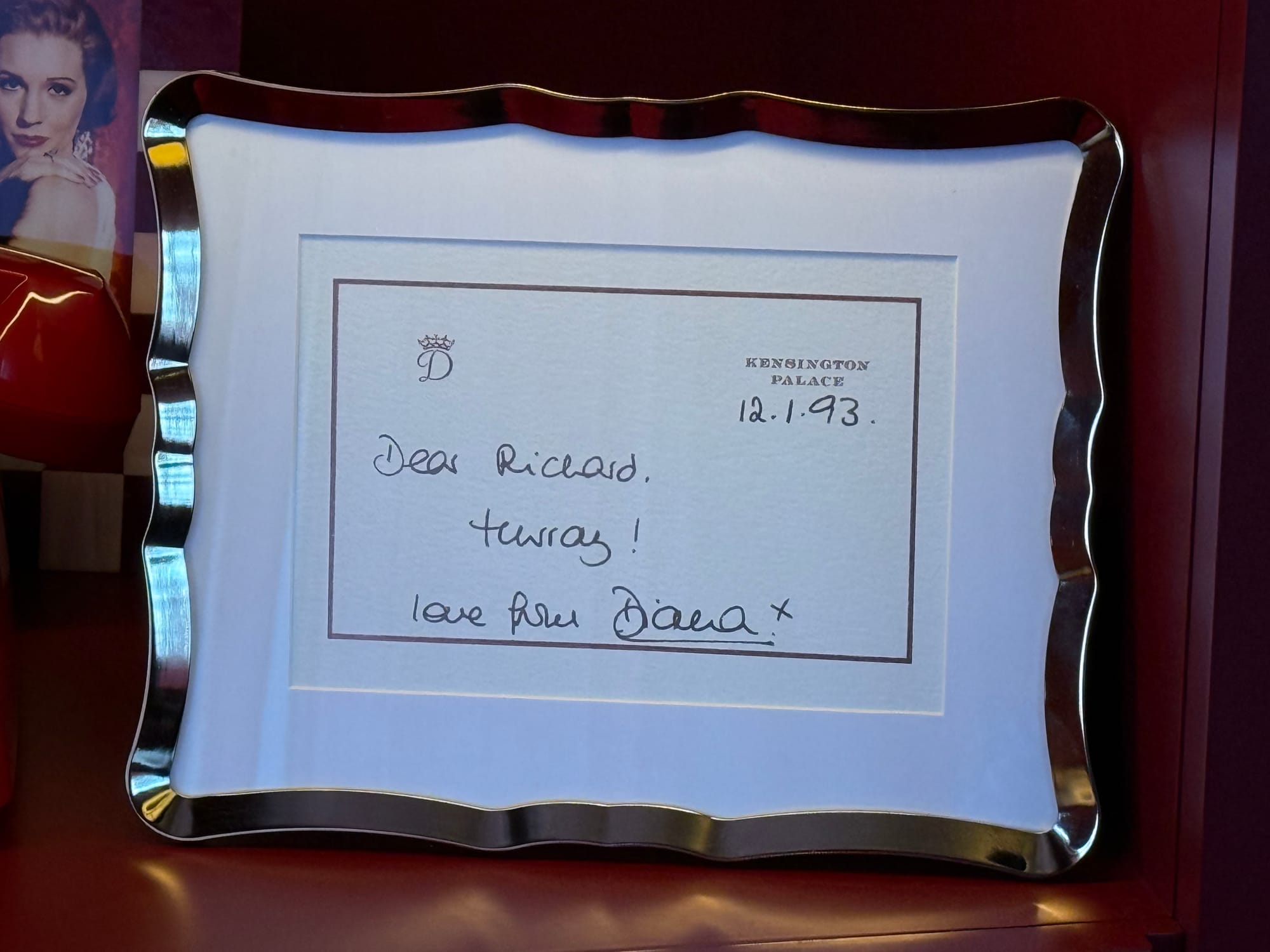 Framed notecard: monogram with letter D with a crown on top, with Kensington Palace printed on it. Dated 12.1.93: “Dear Richard, Hurray! love from Diana. x”