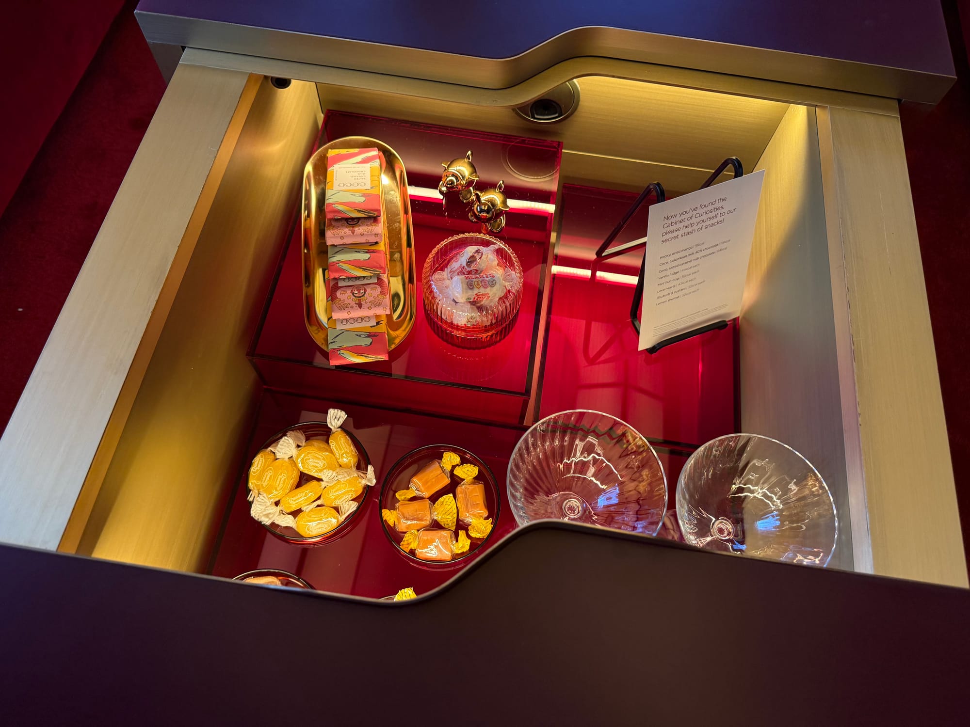 Closeup on the Cabinet of Curiosities: different types of sweets in small bowls inside the coffee table with sliding top from the first photo in this section.