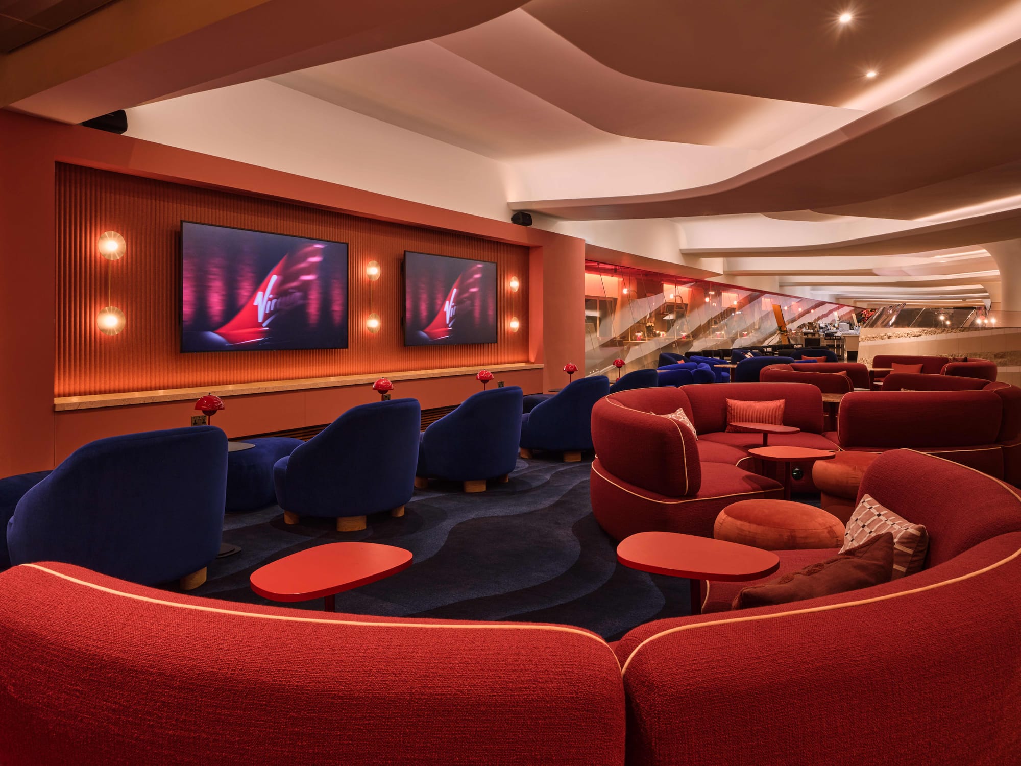 PR shot, evening, showing the blue chairs, red sofas and the TVs — which are showing Virgin Atlantic tails.