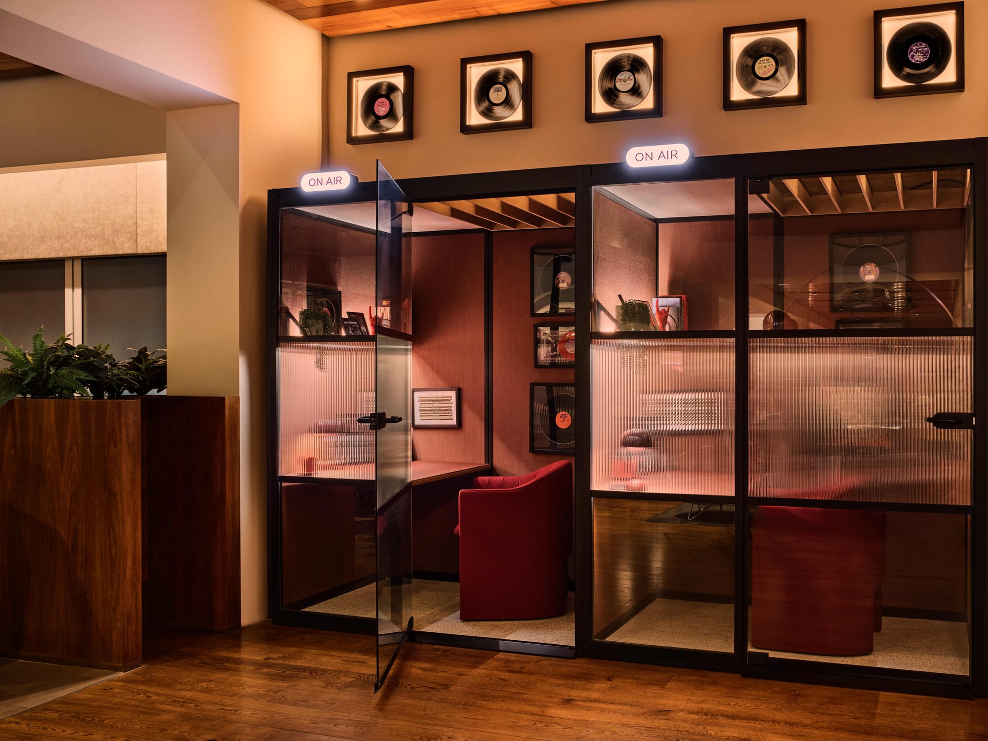 PR snap of two work pods, containing desks, a red desk-height armchair, framed records, and other tchotchkes