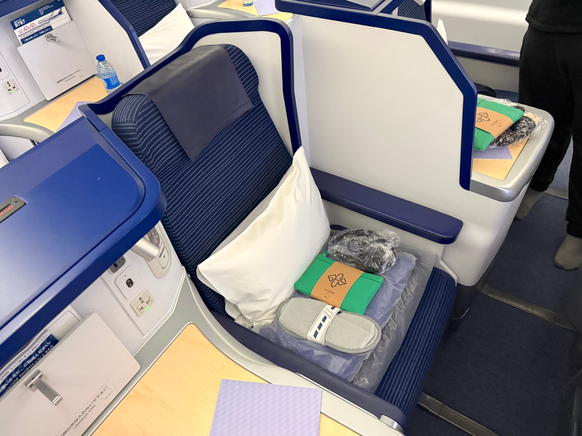 Skylounge seat, centre section, away-from-aisle variant. Ther’es a lot of white thermoplastic, medium and dark blue, and pale woods.