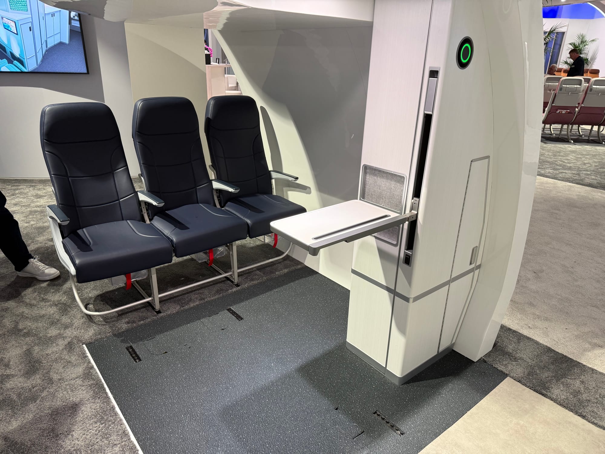 Collins Prime mockup. Three economy seats are behind what is clearly a four-point wheelchair securement point system on the floor. A 1/3-width monument extends a fold-out table.