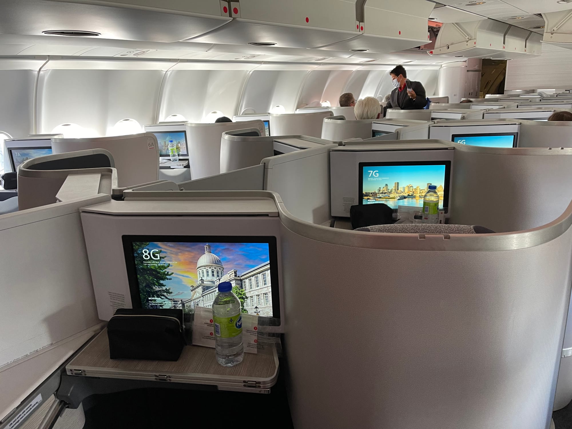 Looking across the cabin of an Air Canada A330 with Super Diamond seats. It’s almost entirely grey with the exception of screens showing Montréal architecture.