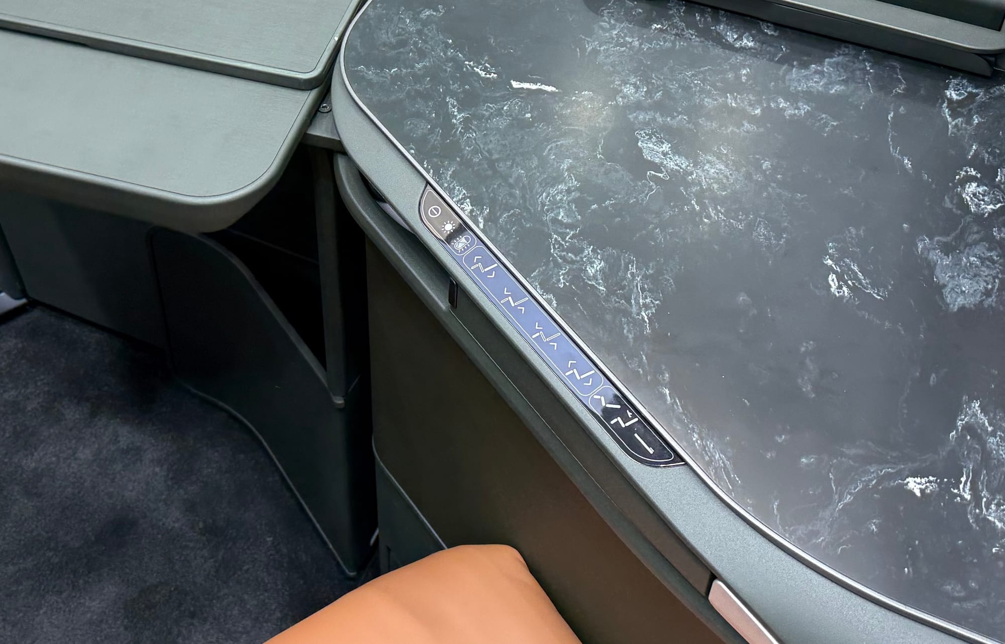 Fourteen capacitative seat controls (do not disturb, lights, seat motion, presets) in a line with no raised element or other non-visual way to see them.