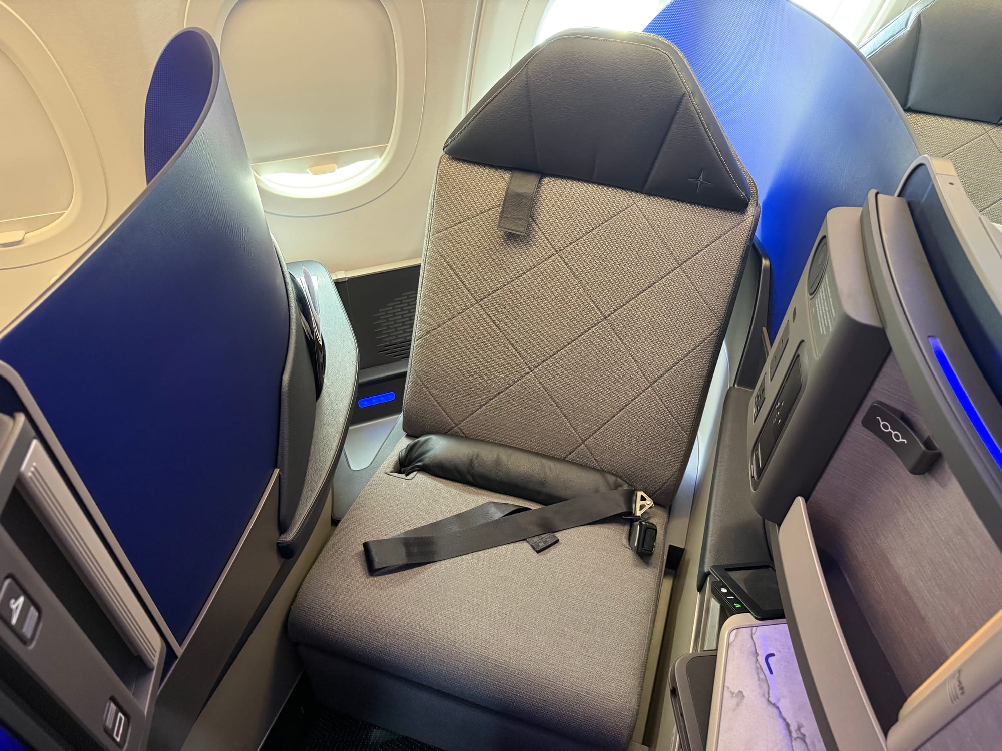 Looking down on the seat from above in seat mode, showing both a thick airbag belt and an over-shoulder third point belt.