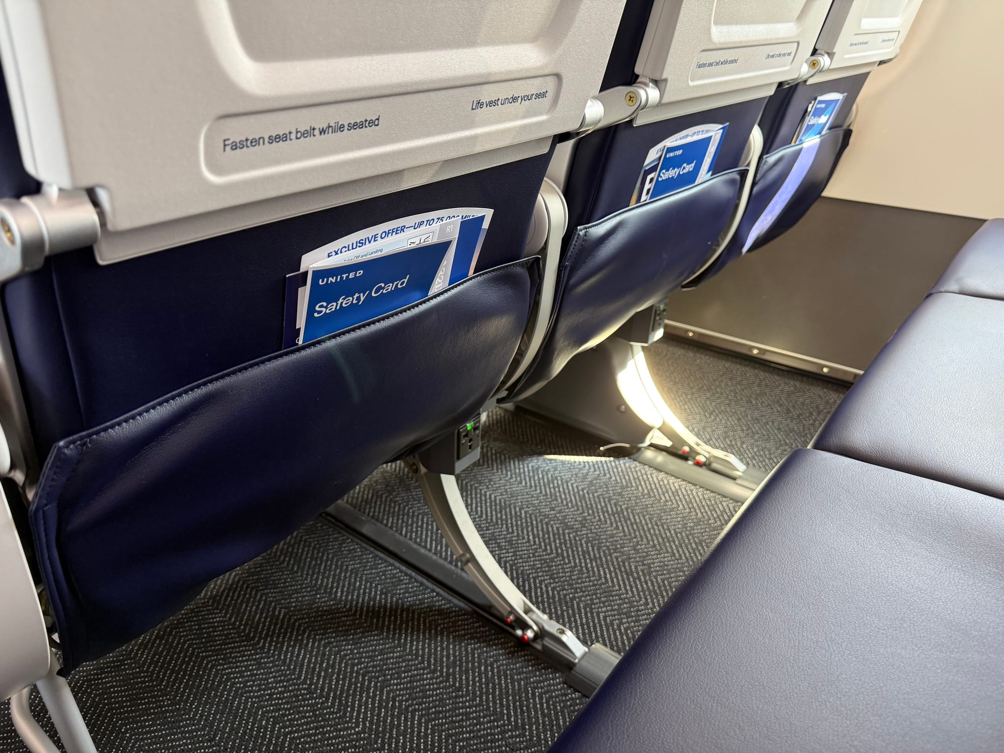 The shin clearance area of a row of economy class seats, looking quite tight.