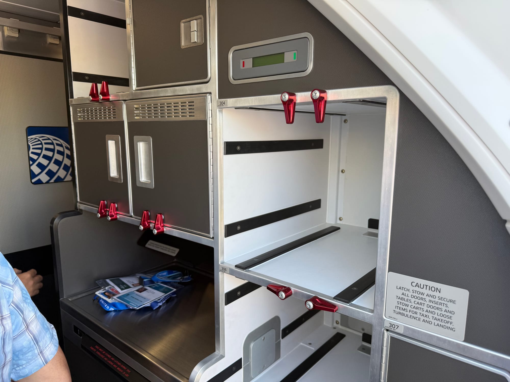 The rear-facing left hand side galley, with some airshow lanyard passes on the surface. A small hatch is opening behind them.