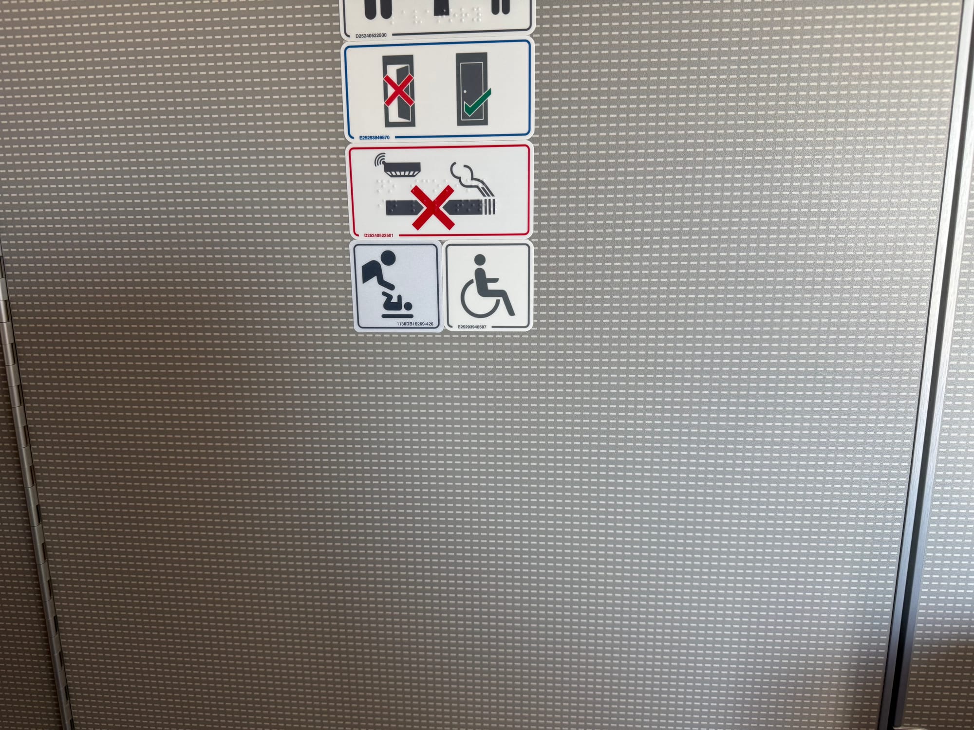 A lavatory door with various placards including a wheelchair icon.