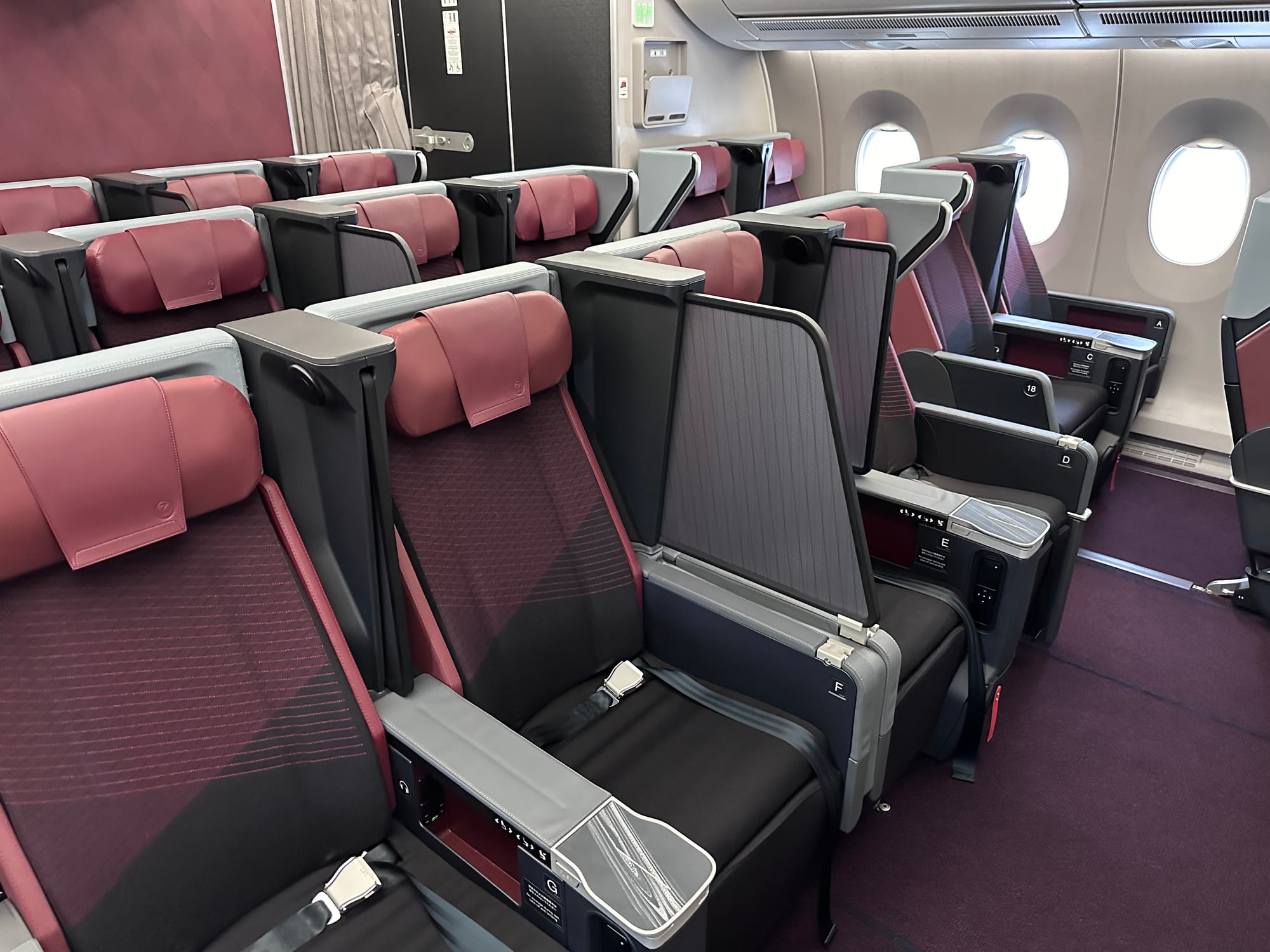 A red, black and grey premium economy cabin in 2-4-2 on an A350. It has a high privacy divider and an extra-extended one between the centre two seats of the middle quad.
