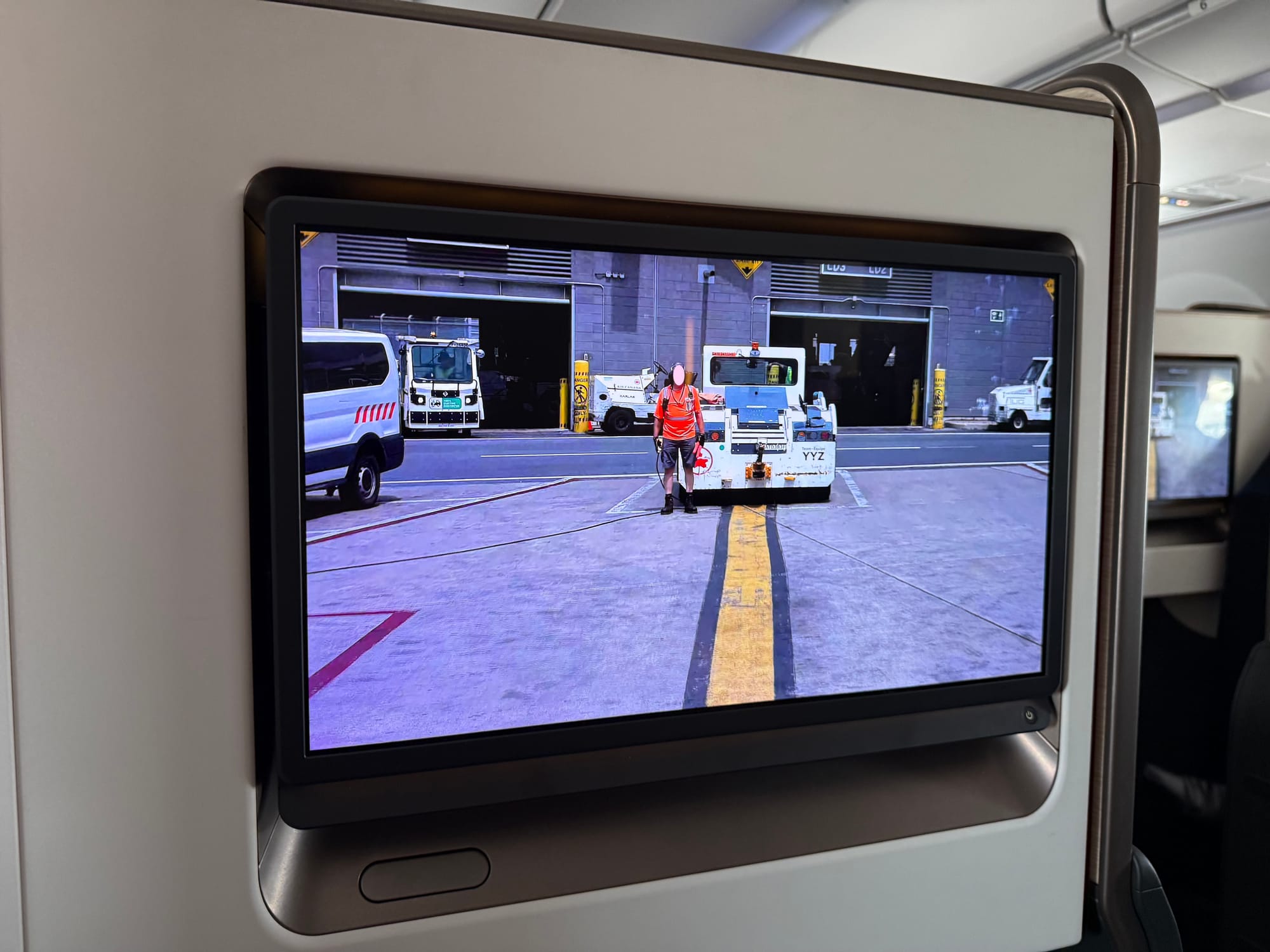 An Astrova screen in a Collins Aurora housing. It shows a 4K highly detailed image of a ground handler, whose face is blurred out.