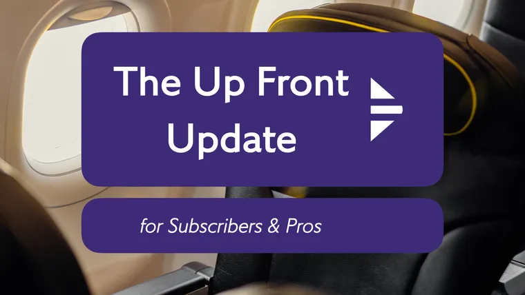 Interior, airline cabin. A large black recliner seat with yellow trim, with the Update logo superimposed.
