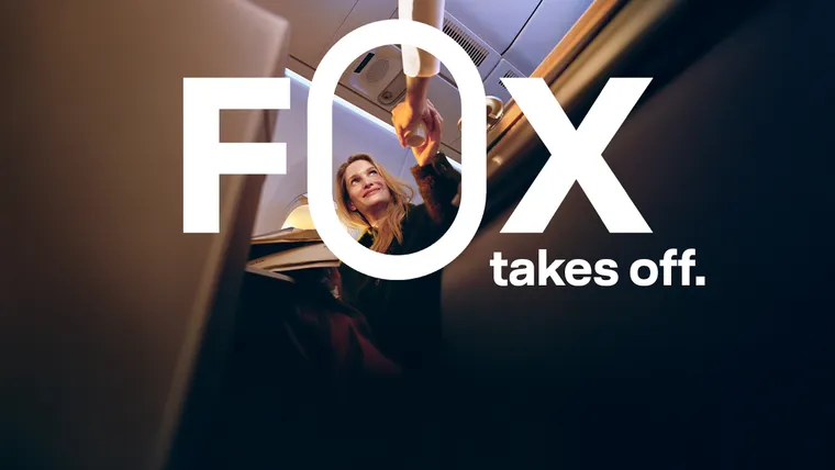 A passenger in business class receives a drink from, presumably, a flight attendant.