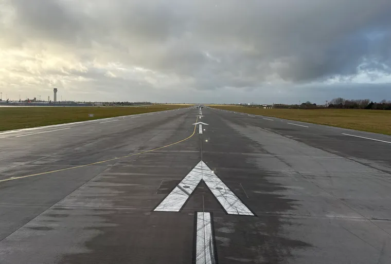 A shot straight down a wet runway with clouds overhead at Dublin Airport.