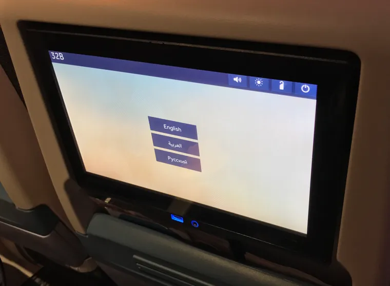 A RAVE IFE system, seat 32B, offering English, Arabic and Russian on the splash screen.