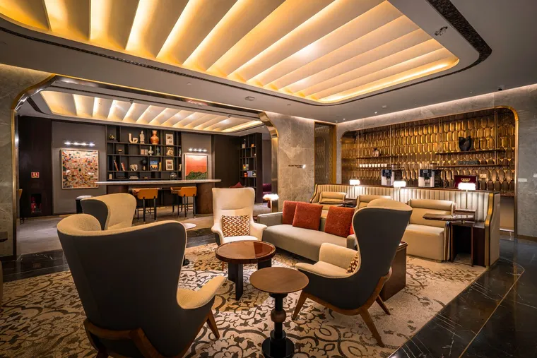 Airline lounge, with several types of seaitng. The aesthetic is plush, gold, warm and expensive.