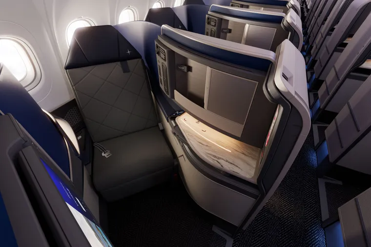 An inward-facing herringbone suite on an A321neo. It is in dark greys, blues and stone.