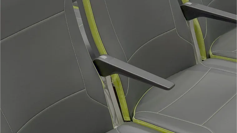 Closeup on a grey slimline seat with light green trim, around the armrest area.