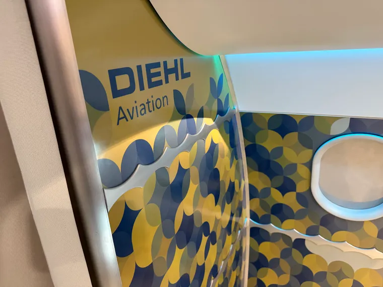 Interior, cabin mockup. Diehl Aviation logo in blue on yellow background. Repeating oval-star motifs in yellow-and-blue-which-make-green.