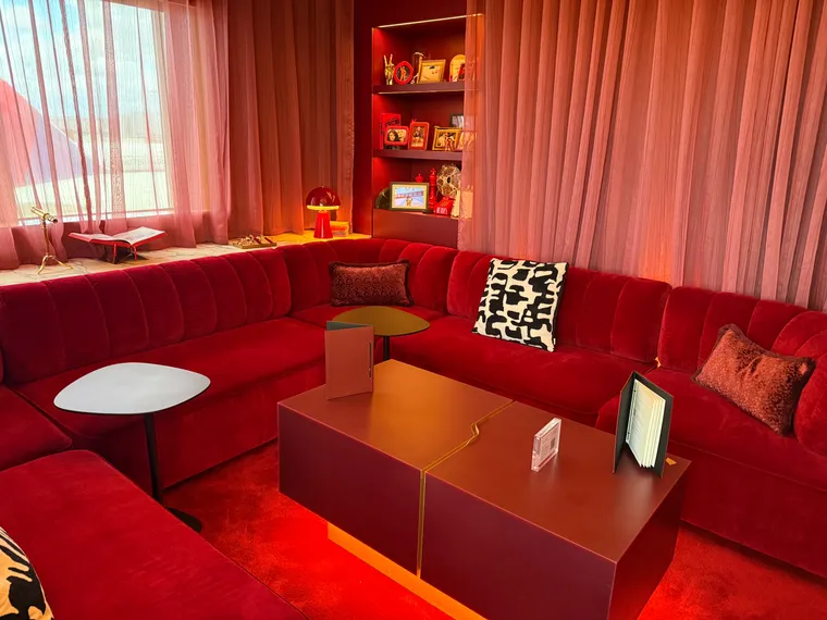Interior, The Royal Box. U-shaped red velvet sofas with red curtains, carpet and furnishings, looking glam.