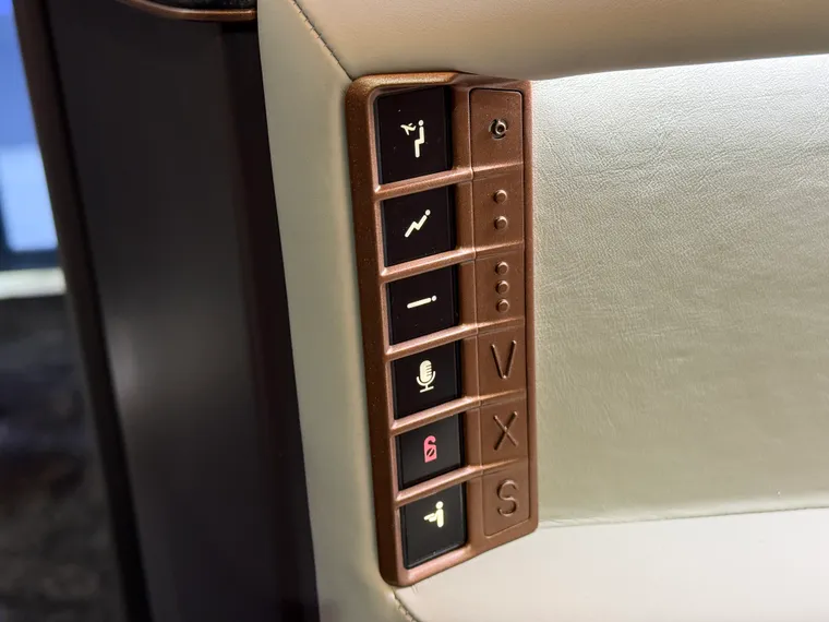 Closeup of Recaro business class seat control, with six capacitative seat control buttons next to raised tactile dots and letters.