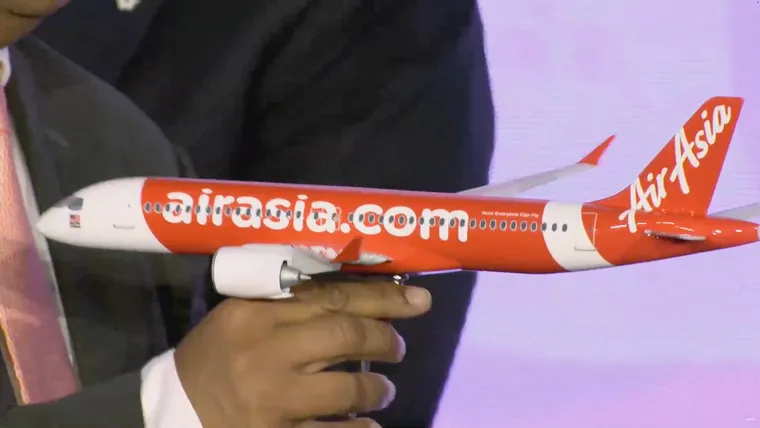 A grainy image of an AirAsia A220-300 with two overwing doors