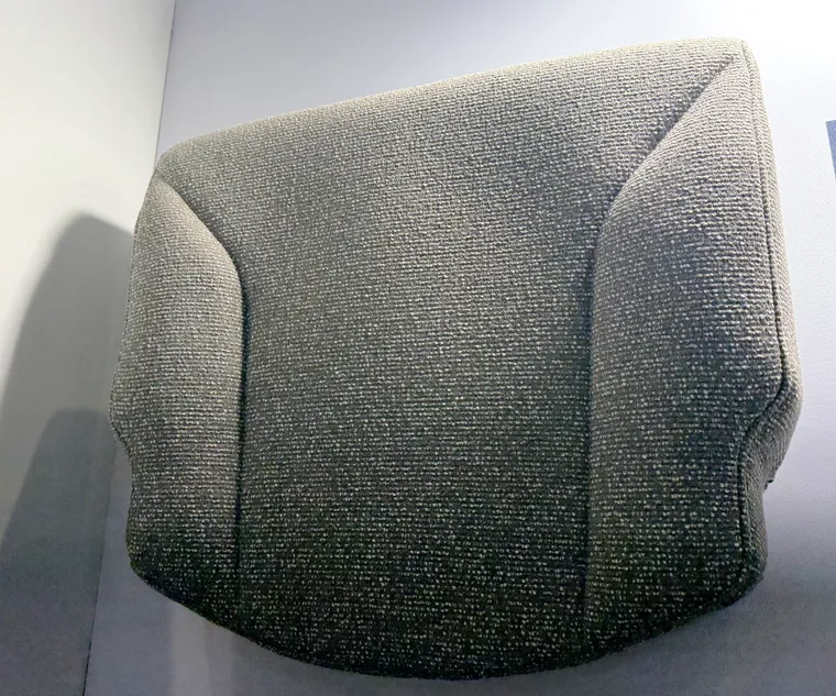 A wall-mounted seat cushion on display with a textured light-green, slightly bobble-effect, dress cover on it