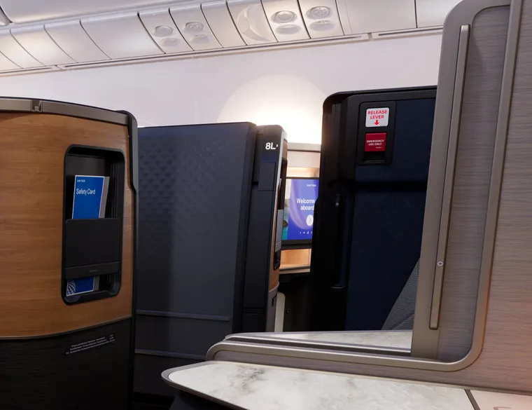 Rendering: cabin closeup of the doors of a business class suite, with the emergency egress lever’s red-and-white placards clearly visible