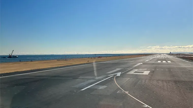 Under a blue sky, looking down the runway at Tokyo Haneda